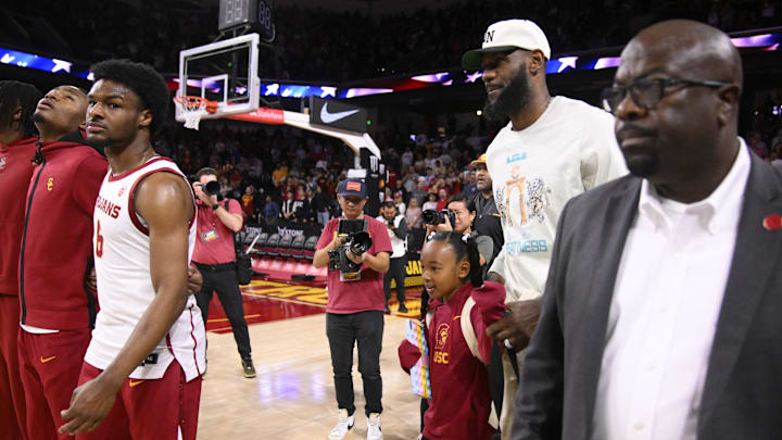 Dec 10, 2023; Los Angeles, California, USA; LeBron James heads to his courtside seats as his son Bronny James stands pregame.