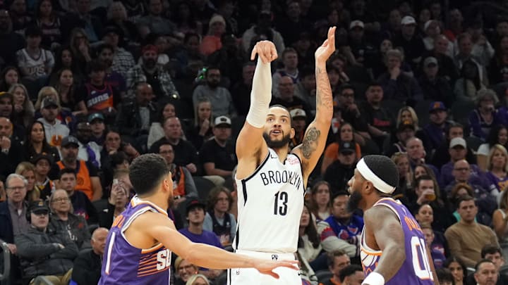 Nov 27, 2024; Phoenix, Arizona, USA; Brooklyn Nets guard Tyrese Martin (13) shoots over Phoenix Suns guard Devin Booker (1) and Phoenix Suns forward Royce O'Neale (00) during the second half at Footprint Center. Mandatory Credit: Joe Camporeale-Imagn Images