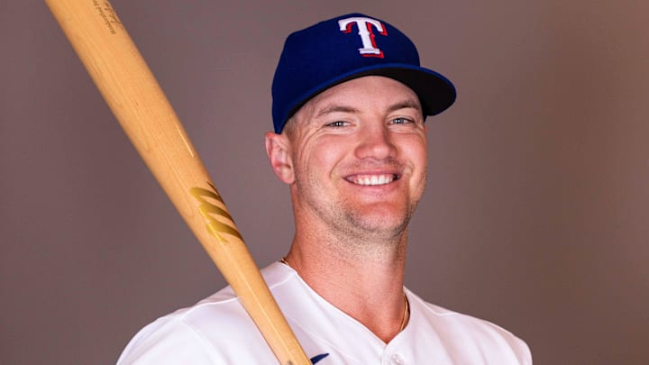 Texas Rangers infielder Josh Jung smiles as he holds a bat on his shoulder.
