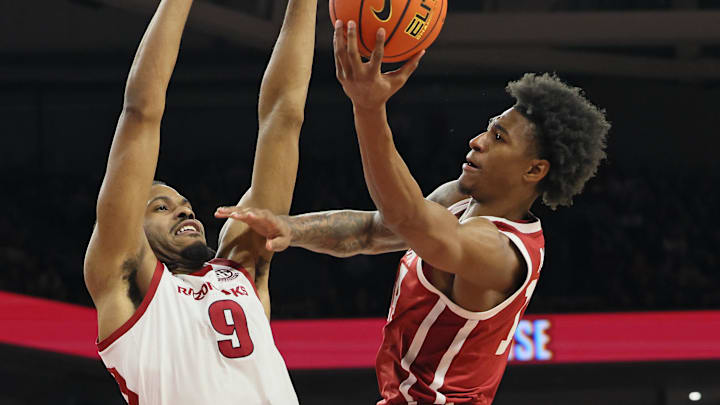 Oklahoma Sooners forward Jalen Moore (14) shoots in the first half as Arkansas Razorbacks forward Jonas Aidoo (9) defends at Bud Walton Arena.