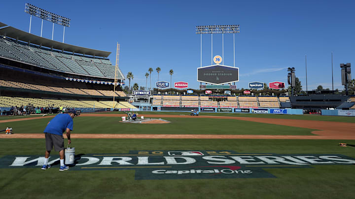 Oct 24, 2024; Los Angeles, CA, USA; Stadium workers paint the World Series logo on the field prior to team workouts at Dodgers Stadium. Mandatory Credit: Kirby Lee-Imagn Images