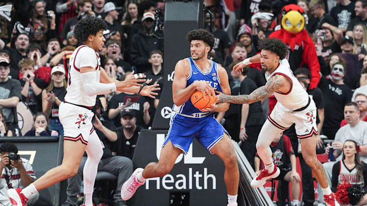 Duke Blue Devils forward Cameron Boozer (12) looks to pass as Louisville Cardinals guard J'vonne Hadley (1) at right pressures during ACC college basketball January 6, 2026 in Louisville, Kentucky.