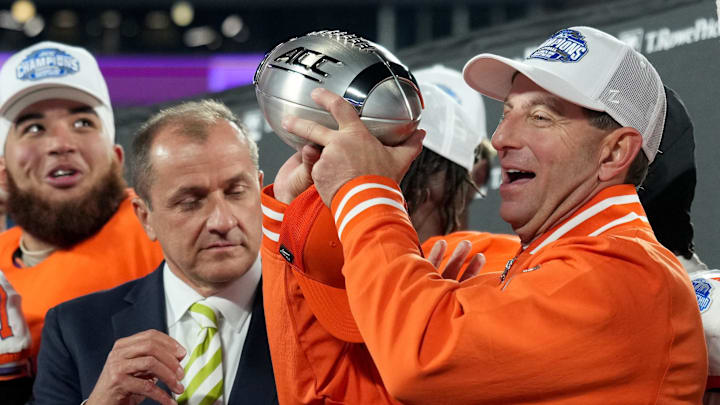 Dec 7, 2024; Charlotte, NC, USA; ACC commissioner James Phillips presents Clemson Tigers head coach Dabo Swinney with the trophy after the Tigers won the 2024 ACC Championship game against the Southern Methodist Mustangs at Bank of America Stadium. Mandatory Credit: Jim Dedmon-Imagn Images