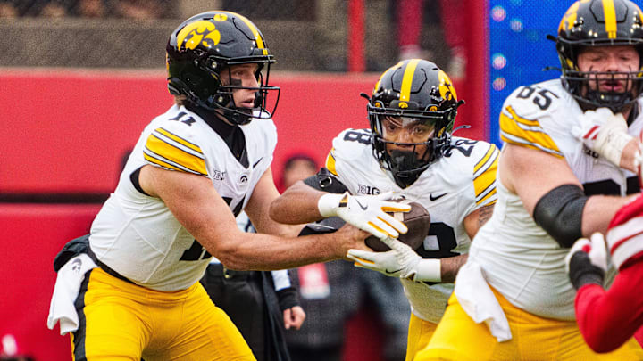 Iowa Hawkeyes quarterback Mark Gronowski (11) hands the ball off to running back Kamari Moulton (28) 