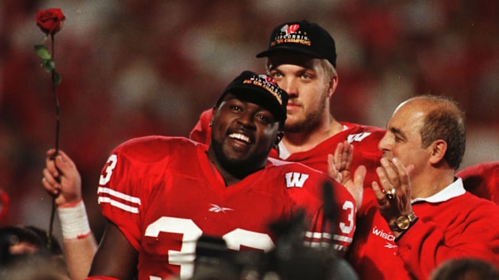 University of Wisconsin running back Ron Dayne is all smiles during a ceremony honoring the season and his record run at the end of the victory over Iowa on Nov. 13, 1999, at Camp Randall Stadium in Madison. Behind, Chris McIntosh and coach Barry Alvarez applaud his efforts.
