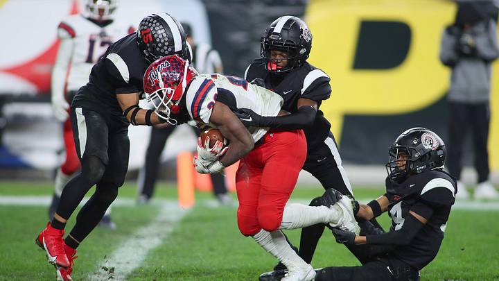Aliquippa's QaLil Goode (14), Gavin Wilcox (13), and Arison Walker (15) attempt to hold back McKeesport's Kemon Spell (20) from scoring a touchdown during the second half of the WPIAL 4A Championship game Friday evening at Acrisure Stadium in Pittsburgh, PA.