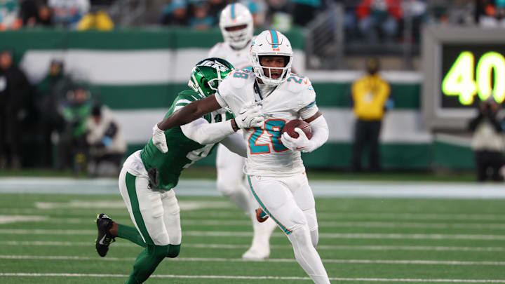 Jan 5, 2025; East Rutherford, New Jersey, USA; Miami Dolphins running back De'Von Achane (28) runs with the ball while New York Jets cornerback D.J. Reed (4) attempts to tackle him during the first quarter at MetLife Stadium. Mandatory Credit: Ed Mulholland-Imagn Images