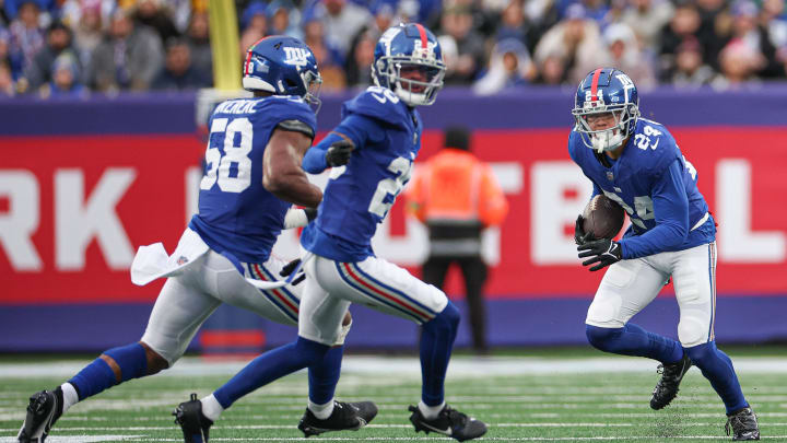 Dec 31, 2023; East Rutherford, New Jersey, USA; New York Giants safety Dane Belton (24) returns an interception as cornerback Cor'Dale Flott (28) and linebacker Bobby Okereke (58) turn to block during the second half against the Los Angeles Rams at MetLife Stadium.  