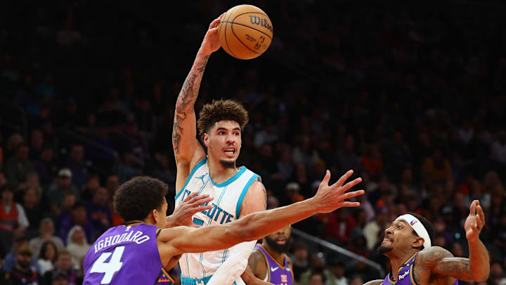 Jan 12, 2025; Phoenix, Arizona, USA; Charlotte Hornets guard LaMelo Ball (1) passes the ball past Phoenix Suns center Oso Ighodaro (4) during the second half at Footprint Center. Mandatory Credit: Mark J. Rebilas-Imagn Images