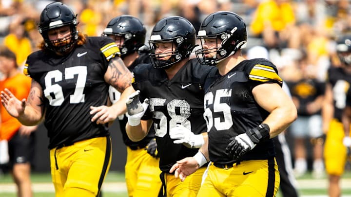 Aug 9, 2025; Iowa offensive linemen Gennings Dunker (67) Kade Pieper (58) and Logan Jones (65) run a drill during the Hawkeyes Kids Day NCAA football open practice at Kinnick Stadium in Iowa City, Iowa. Mandatory Credit: Joseph Cress for the Des Moines Register