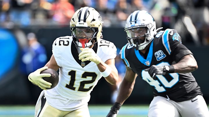 Nov 3, 2024; Charlotte, North Carolina, USA; New Orleans Saints wide receiver Chris Olave (12) with the ball as Carolina Panthers linebacker Charles Harris (40) defends in the first quarter at Bank of America Stadium. Mandatory Credit: Bob Donnan-Imagn Images
