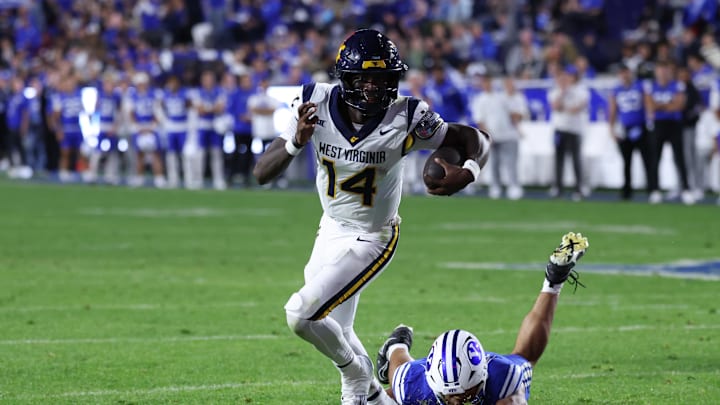 Oct 3, 2025; Provo, Utah, USA; West Virginia Mountaineers quarterback Khalil Wilkins (14) breaks a tackle by Brigham Young Cougars linebacker Siale Esera (54) during the third quarter at LaVell Edwards Stadium. Mandatory Credit: Rob Gray-Imagn Images