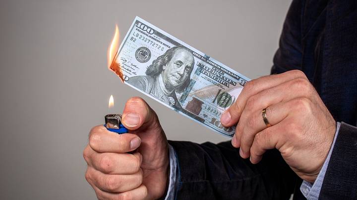 Person holding a lighter to a $100 bill Person holding a lighter to a $100 bill
