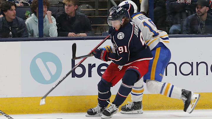 Feb 23, 2024; Columbus, Ohio, USA; Columbus Blue Jackets left wing Kent Johnson (91) avoids the check of Buffalo Sabres center Peyton Krebs (19) during the third period at Nationwide Arena. Mandatory Credit: Russell LaBounty-Imagn Images