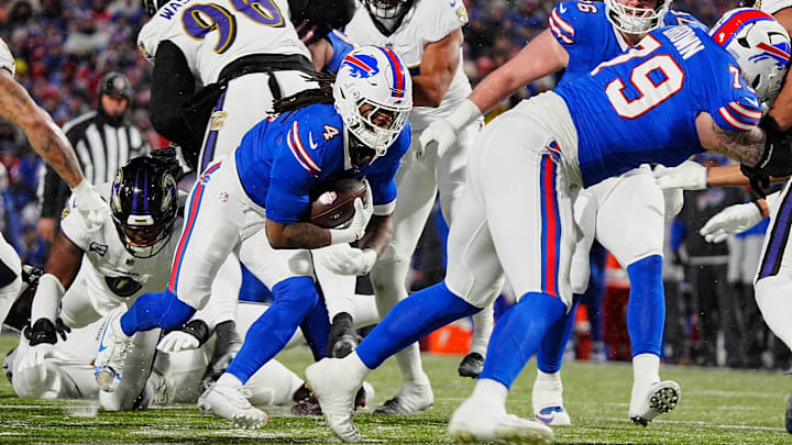 Buffalo Bills running back James Cook, carrying the ball, keeps low as teammate Buffalo Bills offensive tackle Spencer Brown blocks opening a spot for him during first half action at the Buffalo Bills divisional game against the Baltimore Ravens at Highmark Stadium in Orchard Park on Jan. 19, 2025.