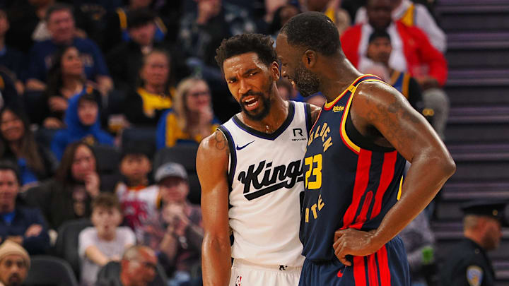 Jan 5, 2025; San Francisco, California, USA; Sacramento Kings guard Malik Monk (0) and Golden State Warriors forward Draymond Green (23) between plays during the third quarter at Chase Center. Mandatory Credit: Kelley L Cox-Imagn Images