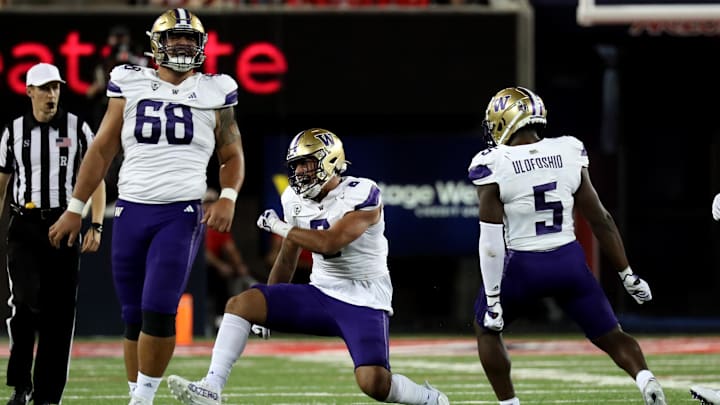 Ulumoo Ale (68) celebrates a defensive stop with UW teammates Bralen Trice (8) and Edefuan Ulofoshio (5) in 2023 against Arizona.