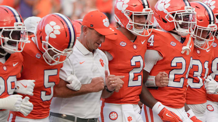 Clemson head coach Dabo Swinney arm-in-arm with defensive back Ronan Hanafin (5) and quarterback Cade Klubnik (2) and teammates during the “Walk of Champions” march to the end zone, before the game with Clemson and Louisiana State University at Memorial Stadium in Clemson, S.C. Saturday, August 30, 2025.