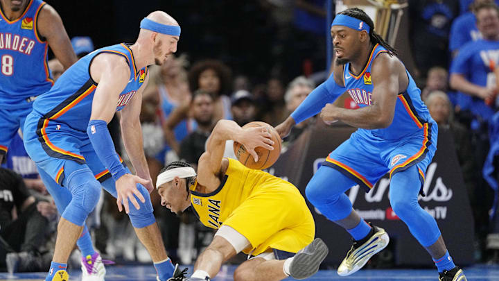 Jun 8, 2025; Oklahoma City, Oklahoma, USA; Indiana Pacers guard Andrew Nembhard (2) falls with the ball against Oklahoma City Thunder guard Alex Caruso (left) and guard Luguentz Dort (right) during the second half during game two of the 2025 NBA Finals at Paycom Center. Mandatory Credit: Kyle Terada-Imagn Images