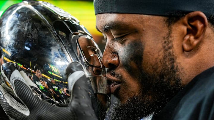 Oregon Ducks defensive back Tysheem Johnson (0) kisses the Big Ten trophy Sunday, Dec. 8, 2024, after the Big Ten Championship game at Lucas Oil Stadium in Indianapolis. The Oregon Ducks defeated the Penn State Nittany Lions, 45-37.