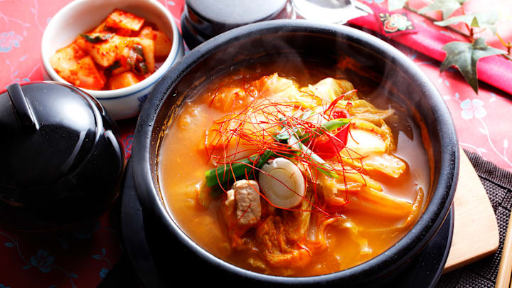 Korean stew in pot with kimchi on the side.