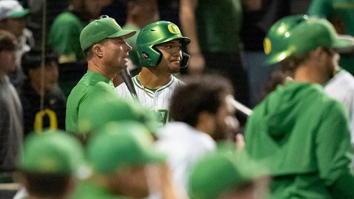 Oregon head coach Mark Wasikowski, left, and Naulivou Lauaki Jr. meet before an at-bat in extra innings as the Oregon Ducks host the USC Trojans on May 14, 2026, in Eugene, Oregon.