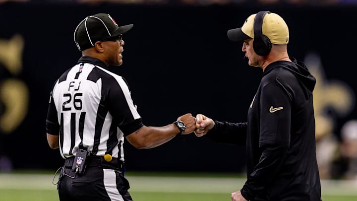 Dec 29, 2024; New Orleans, Louisiana, USA;  New Orleans Saints interim head coach Darren Rizzi fist bumps field judge Jabir Walker (26) during the first half at Caesars Superdome. Mandatory Credit: Stephen Lew-Imagn Images