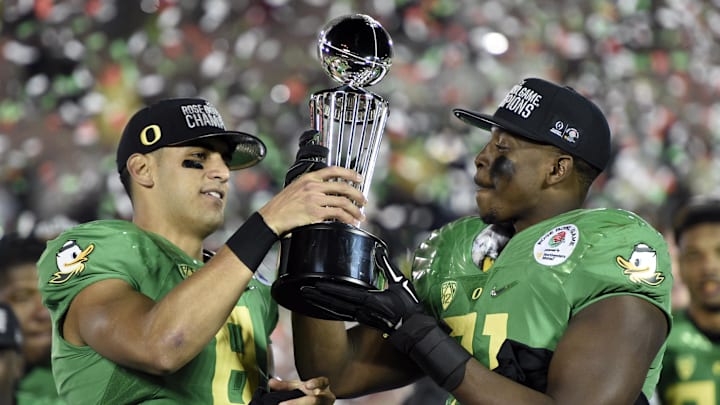 Jan 1, 2015; Pasadena, CA, USA; Oregon Ducks quarterback Marcus Mariota (8) and linebacker Tony Washington (91) hold up the Rose Bowl trophy.
