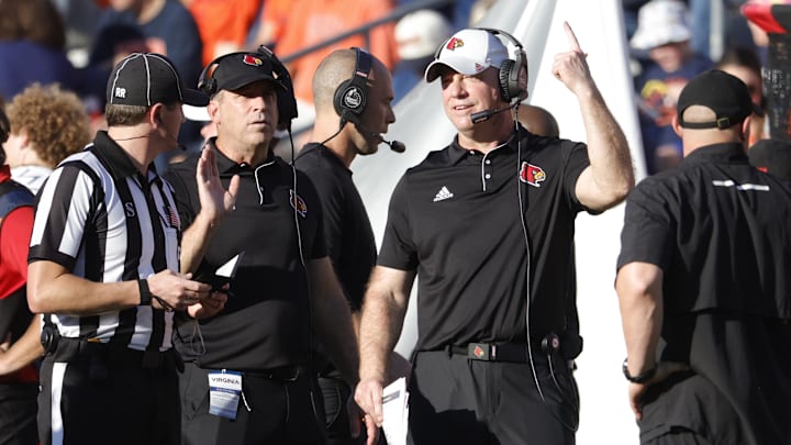 Oct 12, 2024; Charlottesville, Virginia, USA; Louisville Cardinals head coach Jeff Brohm (center) questions a call against the Virginia Cavaliers during the first half at Scott Stadium. Mandatory Credit: Amber Searls-Imagn Images