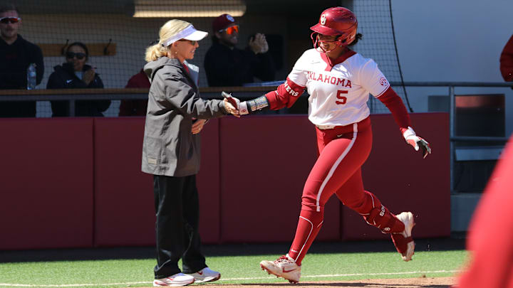 Oklahoma outfielder Ella Parker high fives Patty Gasso after hitting a home run against Kentucky.