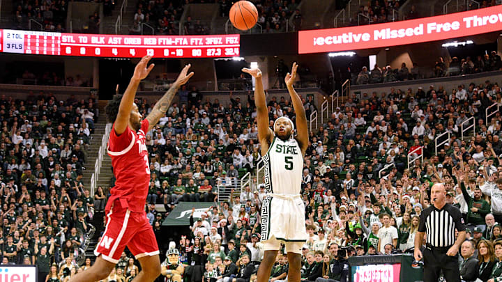 Dec 7, 2024; East Lansing, Michigan, USA;  Michigan State Spartans guard Tre Holloman (5) puts in a three point shot over Nebraska Cornhuskers guard Brice Williams (3) during the second half at Jack Breslin Student Events Center. Mandatory Credit: Dale Young-Imagn Images