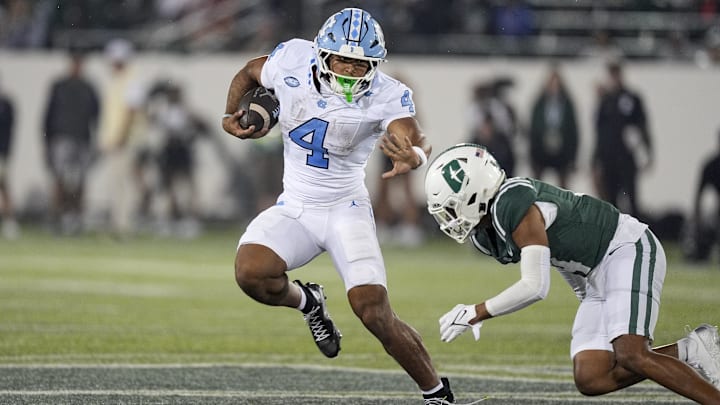 Sep 6, 2025; Charlotte, North Carolina, USA;  North Carolina Tar Heels running back Caleb Hood (4) tries to avoid Charlotte 49ers defensive back Gavin Shipman (4) during the second half at Jerry Richardson Stadium. Mandatory Credit: Jim Dedmon-Imagn Images