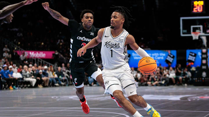 Mar 11, 2026; Kansas City, MO, USA; UCF Knights guard Themus Fulks (1) drives to the basket around Cincinnati Bearcats guard Jizzle James (2) during the first half at T-Mobile Center. Mandatory Credit: William Purnell-Imagn Images