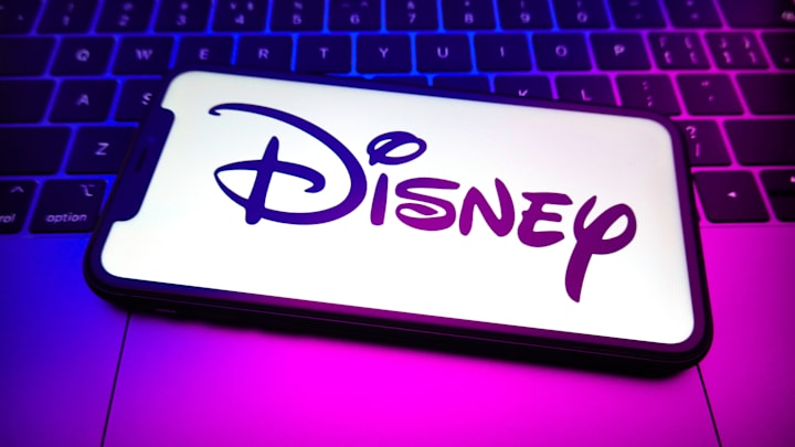 In this photo illustration, a Disney logo is displayed on...