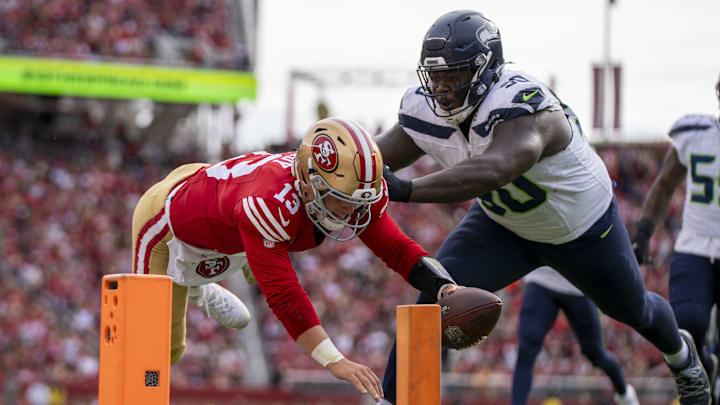 November 17, 2024; Santa Clara, California, USA; San Francisco 49ers quarterback Brock Purdy (13) scores a touchdown against Seattle Seahawks defensive tackle Jarran Reed (90) during the first quarter at Levi's Stadium. Mandatory Credit: Kyle Terada-Imagn Images