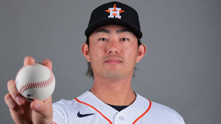 Tatsuya Imai holds a baseball for media day in a black Astros hat and white jerse