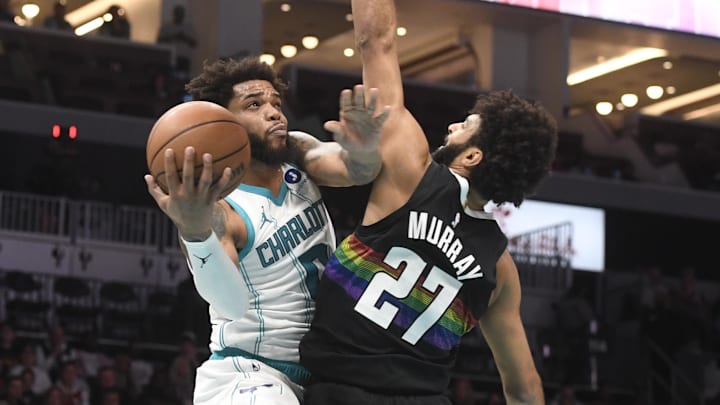 Dec 7, 2025; Charlotte, North Carolina, USA; Charlotte Hornets forward Miles Bridges (0) drives in as he is defended by Denver Nuggets guard Jamal Murray (27) during the first half at the Spectrum Center. Mandatory Credit: Sam Sharpe-Imagn Images