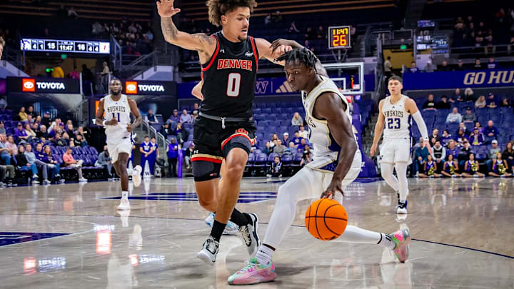 Zoom Diallo makes a move with the ball while fellow Huskies Franck Kepnang and JJ Mandaquit watch.
