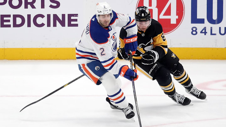 Jan 9, 2025; Pittsburgh, Pennsylvania, USA;  Edmonton Oilers defenseman Evan Bouchard (2) moves the puck against Pittsburgh Penguins left wing Michael Bunting (8) during the third period at PPG Paints Arena. Mandatory Credit: Charles LeClaire-Imagn Images