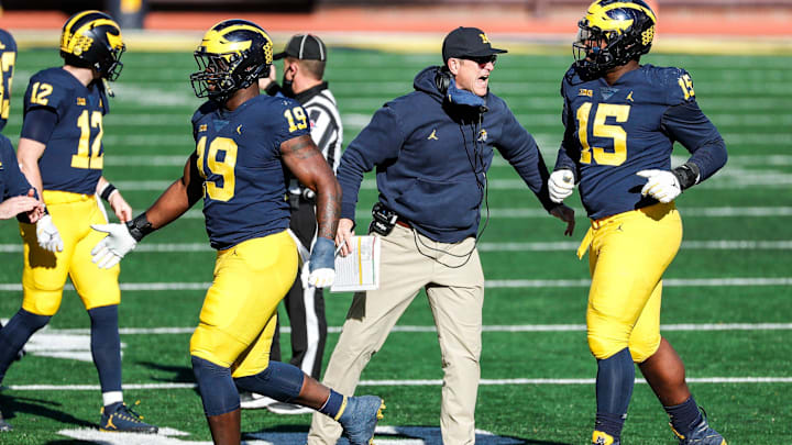 Michigan head coach Jim Harbaugh high fives defensive players as they forced Penn State into a 4th down during the first half at Michigan Stadium in Ann Arbor, Saturday, Nov. 28, 2020.