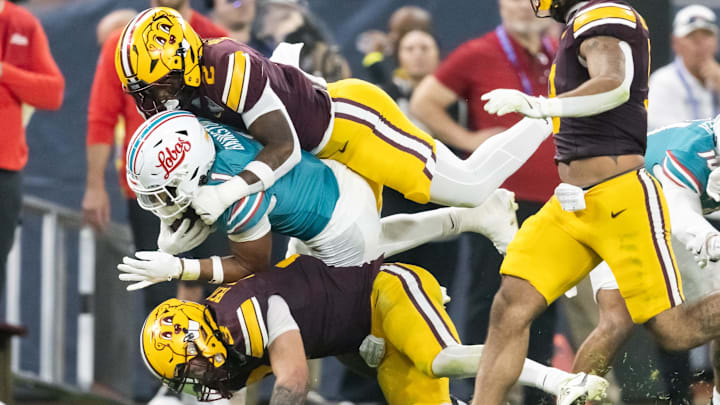Dec 26, 2025; Phoenix, AZ, USA; New Mexico Lobos running back Damon Bankston (1) is tackled by Minnesota Gophers linebacker Emmanuel Karmo (2) and defensive back Koi Perich (3) during the first half of the Rate Bowl at Chase Field. Mandatory Credit: Mark J. Rebilas-Imagn Images