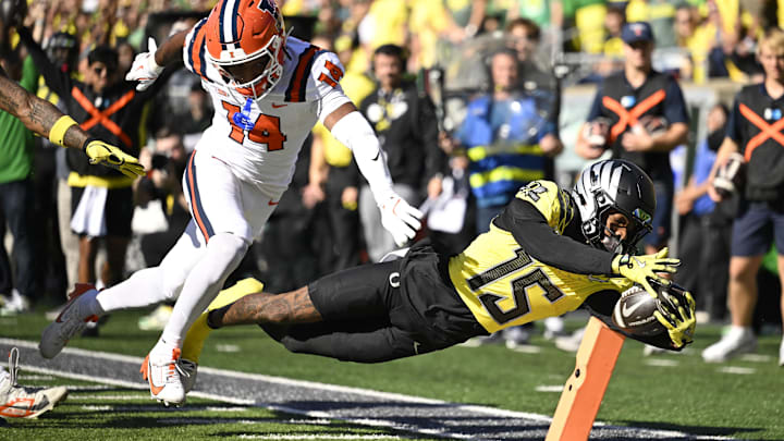 Oct 26, 2024; Eugene, Oregon, USA; Oregon Ducks wide receiver Tez Johnson (15) scores a touchdown during the first half against Illinois Fighting Illini defensive back Xavier Scott (14) at Autzen Stadium. Mandatory Credit: Troy Wayrynen-Imagn Images Oct 26, 2024; Eugene, Oregon, USA; Oregon Ducks wide receiver Tez Johnson (15) scores a touchdown during the first half against Illinois Fighting Illini defensive back Xavier Scott (14) at Autzen Stadium. Mandatory Credit: Troy Wayrynen-Imagn Images