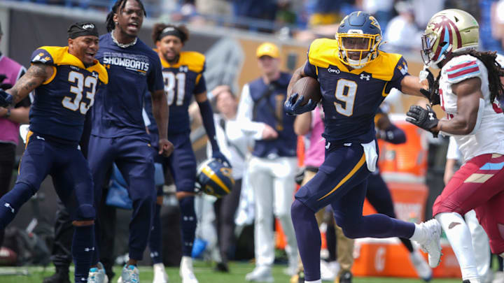 Showboats’ Jonathan Adams stiff arms Panthers’ Kendrick Whitehead as teammates cheer him on from the sidelines.