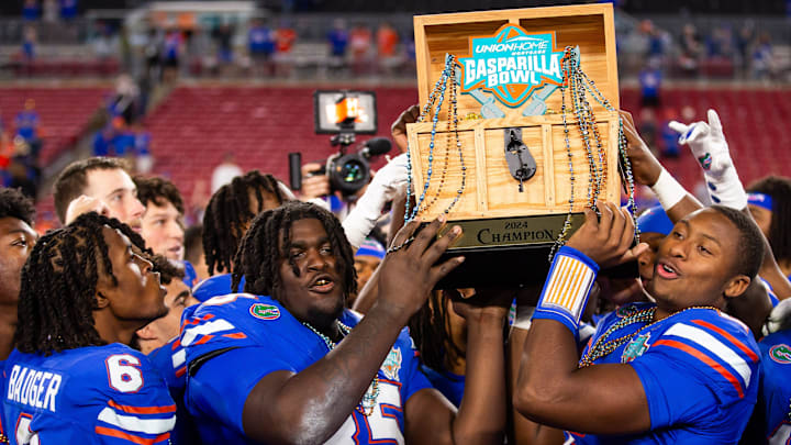 Florida Gators defensive lineman D'Antre Robinson (35) and Florida Gators quarterback DJ Lagway (2) lifts the 2024 Union Home Mortgage Gasparilla Bowl trophyat Raymond James Stadium in Tampa, FL on Friday, December 20, 2024 after defeating Tulane 33-8. [Doug Engle/Gainesville Sun]