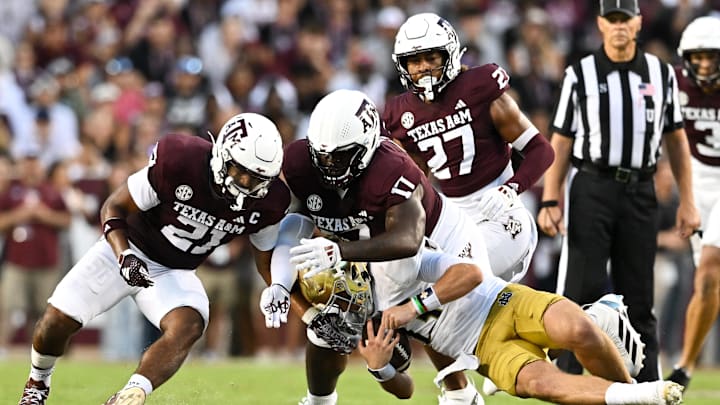 Aug 31, 2024; College Station, Texas, USA;  Texas A&M Aggies linebacker Taurean York (21) and defensive lineman Albert Regis (17) tackle Notre Dame Fighting Irish quarterback Riley Leonard (13) during the second quarter at Kyle Field. Mandatory Credit: Maria Lysaker-Imagn Images