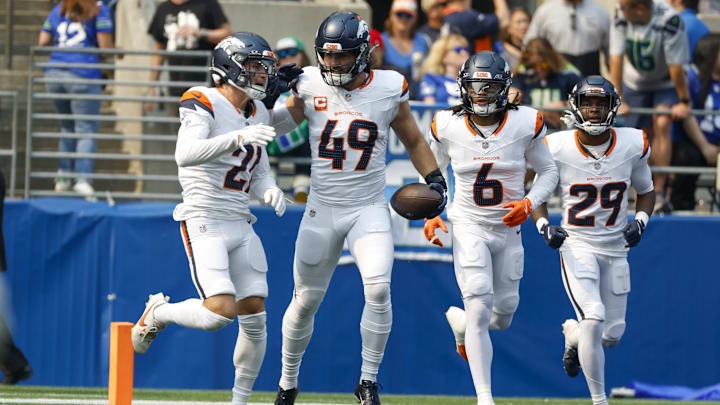 Sep 8, 2024; Seattle, Washington, USA; Denver Broncos linebacker Alex Singleton (49) celebrates with cornerback Riley Moss (21), safety P.J. Locke (6) and cornerback Ja'Quan McMillian (29) after intercepting a pass against the Seattle Seahawks during the first quarter at Lumen Field. 