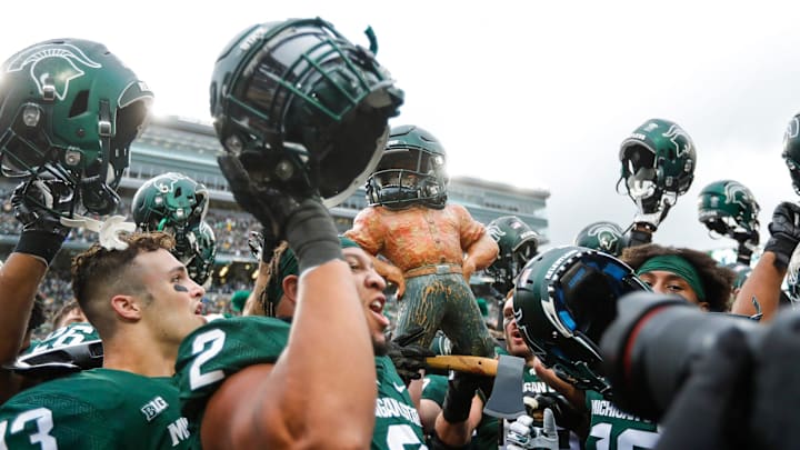 Michigan State players celebrate the 37-33 win over Michigan by raising the Paul Bunyan Trophy at Spartan Stadium in East Lansing on Saturday, Oct. 30, 2021.
