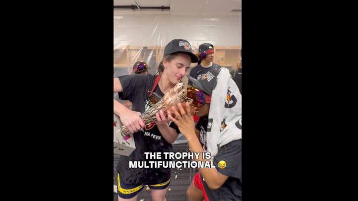 Clark holds the WNBA Commissioner's Cup trophy in the locker room following the Fever's win over the Lynx