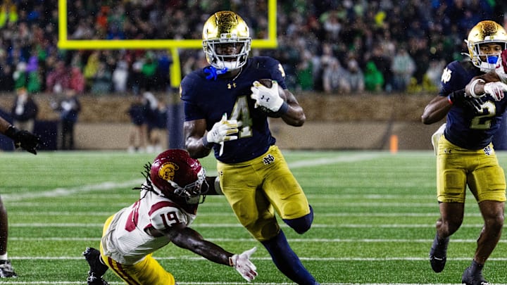 Oct 18, 2025; South Bend, Indiana, USA; Notre Dame Fighting Irish running back Jeremiyah Love (4) runs the ball while Southern California Trojans safety Bishop Fitzgerald (19)  defends in the second half at Notre Dame Stadium. Mandatory Credit: Trevor Ruszkowski-Imagn Images