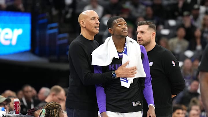 Dec 30, 2024; Sacramento, California, USA; Sacramento Kings guard De'Aaron Fox (center) stands on the sideline with interim head coach Doug Christie (left) and assistant coach Luke Loucks (right) during the fourth quarter against the Dallas Mavericks at Golden 1 Center. Mandatory Credit: Darren Yamashita-Imagn Images